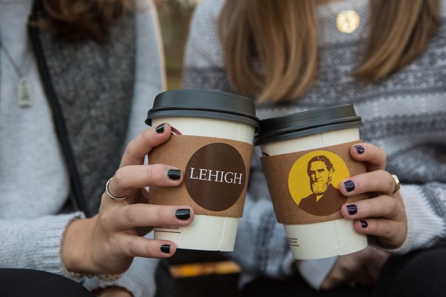 Two female students holding Lehigh University-branded paper coffee cups