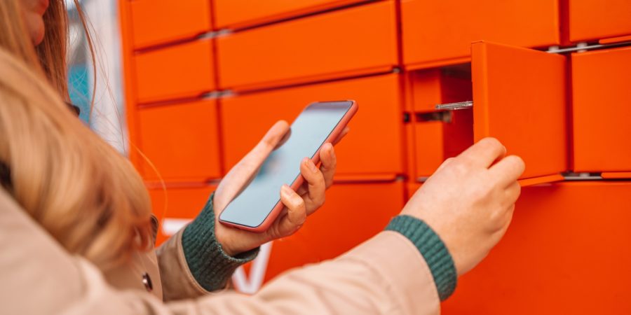 Woman client using automated self service post terminal machine or locker. Mail shipping concept