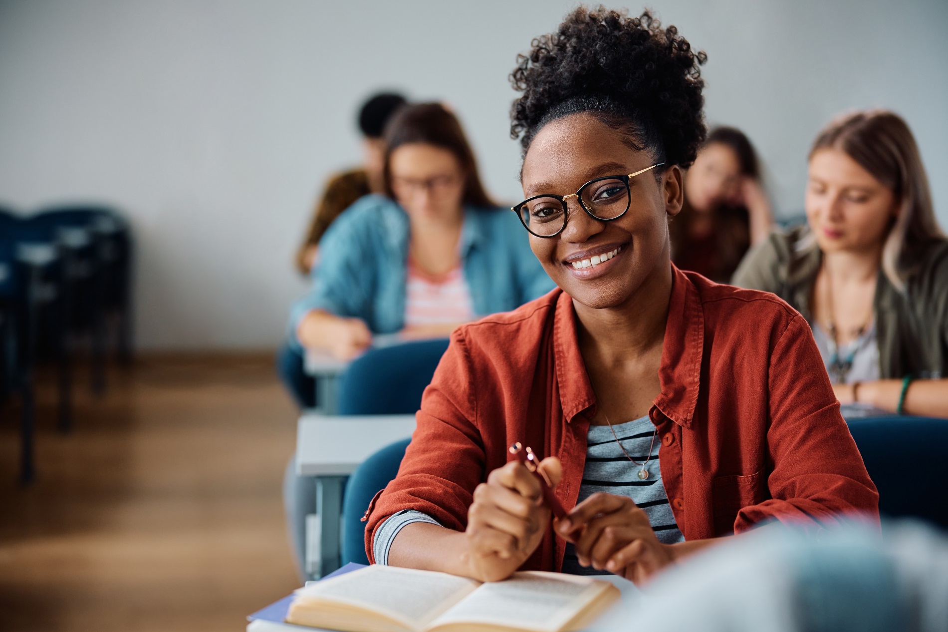 Happy African American woman attending a lecture in university classroom