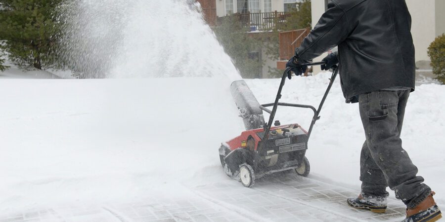 Man removes snow at apartment community with snow blower