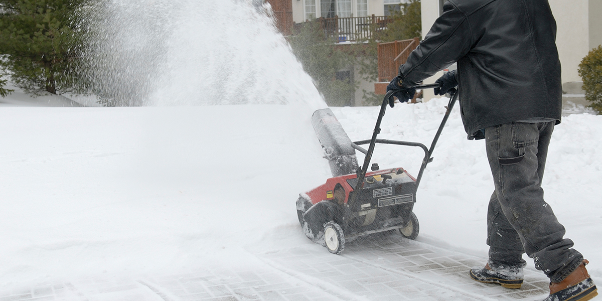 Man removes snow at apartment community with snow blower